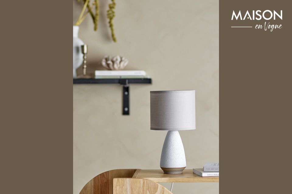 Its sleek design with a sturdy stoneware base and linen shade creates a soft